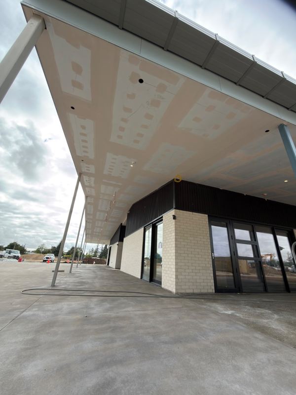 Long commercial canopy soffit plastered and stopped, supported by slim steel columns