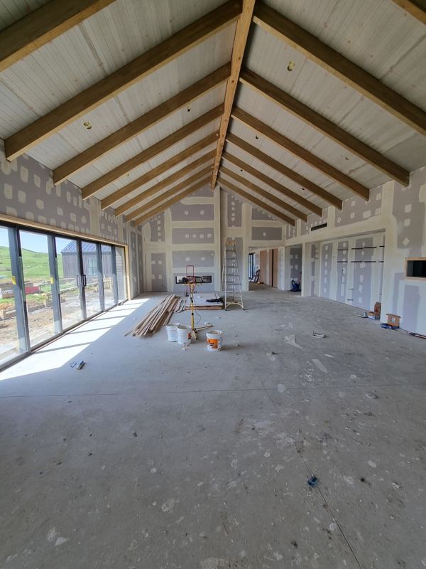 Open-plan home with exposed timber trusses and stopped plasterboard walls